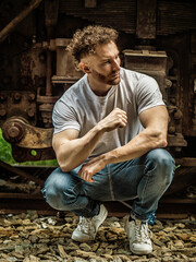 Fototapeta na wymiar Photo of a man sitting on a train track next to a train
