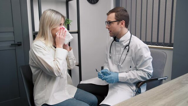 Professional male doctor otolaryngologist doing nose examination with otoscope in modern hospital. Nasal congestion, sinusitis, allergy concept