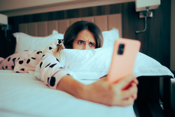 Worried Woman Looking at her phone Lying in Bed. Depressed girl being chronically online upset...