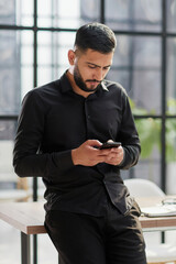 Young casual Businessman holding and using smartphone for sms messages