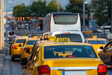 Dense traffic of taxi cars with yellow color and a sign along the city street.