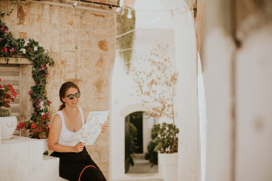 Fototapeta Female tourist with paper city map on narrow streets of Ostuni, Italy
