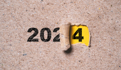 Number of 2024 inside of yellow hole of tear paper for change new year from 2023 to 2024 , Merry...