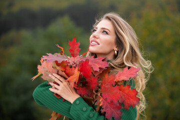 Portrait of young woman with autumn leafs. Romantic girl dream, hold fall maple leaves. Autumnal season.