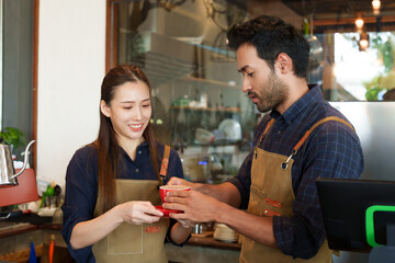 Asian couple together opened this new cafe, standing talking about opening first day shop about what problems should it be resolved, grab cup coffee drink while chatting as cafe closes in evening.