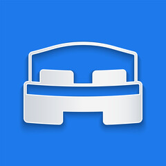 Paper cut Hotel room bed icon isolated on blue background. Paper art style. Vector