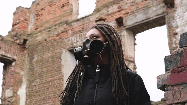 Woman wearing gas mask standing in ruined building. Horizontal slow motion video