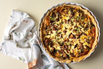 Homemade quiche with seasonal forest mushrooms Chanterelles in a round shape on a yellow background