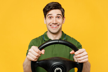 Fototapeta na wymiar Young surprised amazed fun caucasian happy man he wears green t-shirt casual clothes hold steering wheel driving car look camera isolated on plain yellow background studio portrait. Lifestyle concept.