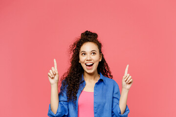 Young amazed happy woman of African American ethnicity in blue shirt casual clothes point index...