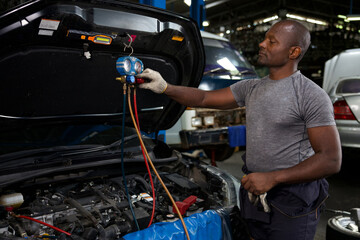 mechanic worker fixing and checking a car air conditioning system in automobile repair shop