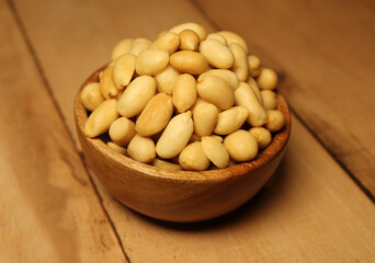Peanut (groundnut and goober) in wooden bowl, used as a snack. Isolated macro food photo wooden beckground
