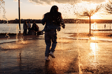 A little beautiful girl runs happily in torn jeans with long flowing hair against the background of a golden sunset.