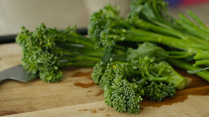 Fresh Broccolini vegetables on a cutting board.