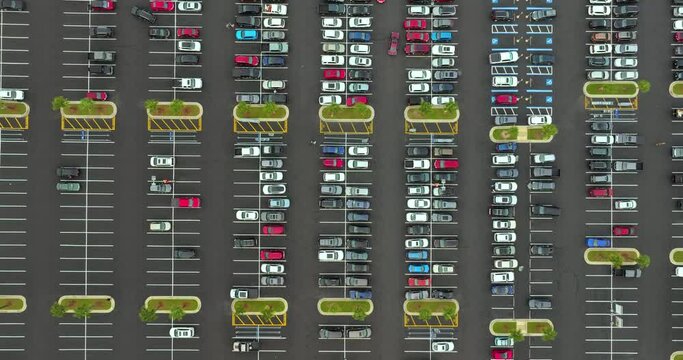 Aerial view of many cars parked on parking lot with lines and markings for parking places and directions. Place for vehicles in front of a grocery mall store