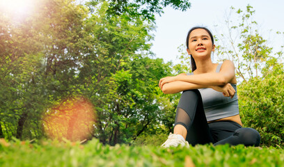 Portrait of happy young beautiful asian woman with healthy and wellness focused wearing sportswear for exercising in park sits relax looking at peaceful nature good mood positive.