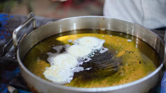 Indian sweet maker making jalegi a fried pretzel dipped in sugar syrup and a popular street food and delicacy served with milk on major festivals like Diwali Dussera