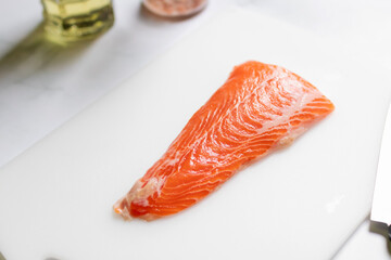 Tail of salmon fillet on white cutting board for delicious salmon steak.