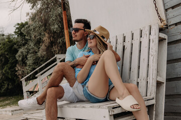 Young romantic couple embracing and smiling while sitting on the wooden pallet outdoors together