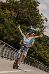 Happy young couple enjoying fun time together while riding electric scooter outdoors together