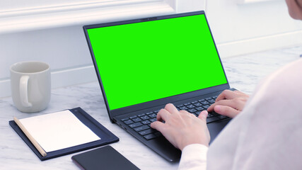 Professional Freelancer Businesswoman works in white office on laptop with green screen. Mock-up...