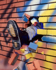 Shoe boot kick breaking bricks wall.