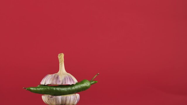 rotating young garlic with hot pepper inside on a red background.Copy space. place for text.