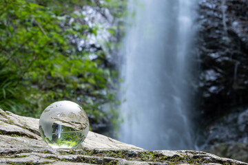 ガラスの地球儀と美しい滝　地球環境に関するイメージ　Glass globe and beautiful waterfall