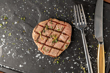 Thinly sliced grilled tenderloin on black stone cutting board