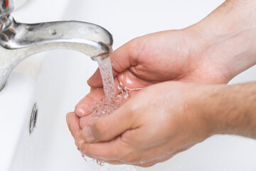 man washes his hands in the bathroom.The best protection against corona virus infection.Corona Virus pandemic protection by cleaning hands frequently.