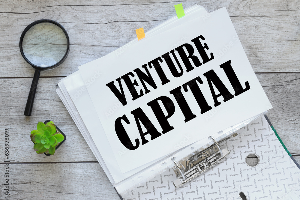 Poster venture capital. white sheet of paper with text on the page. open folder. magnifier