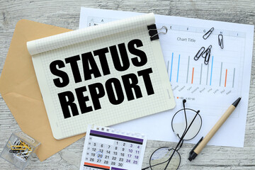 top view of notebook, calendar envelope, financial charts. words STATUS REPORT