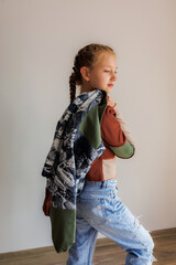 Little girl with blond long hair in two pigtails in new clothes for product demonstration sale in the store