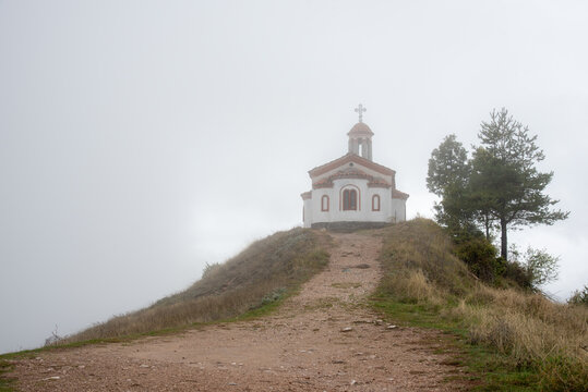 A little chapel on top of a hill in a foggy autumn day