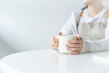 Young woman at home sitting on modern chair relaxing with hot water