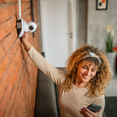 adult caucasian woman adjust prepare home surveillance security camera