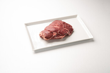 Frische rohe Damwild Keule Braten auf Porzellan und weißem Hintergrund