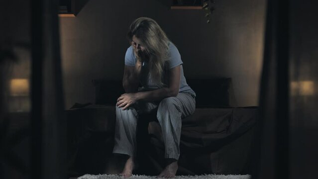 anxiety depression troubled sad female sits on bed in the dark at night,desperate woman can't sleep because of his concern thoughts