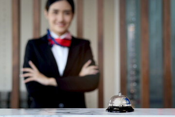 Silver bell on hotel reception service desk with blurred background of smiling beautiful female...