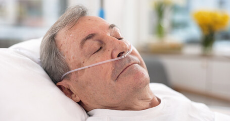Oxygen, hospital bed and senior man sleeping with ventilation and breathing tube support in a...