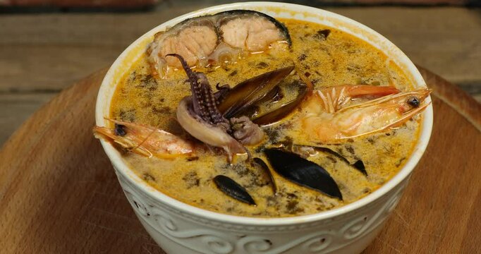Freshly cooked seafood bouillabaisse soup with shrimps, fish fillets and mussels closeup in a bowl on the table.