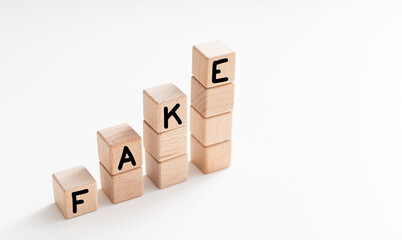 Word FAKE made with wooden cubes on white background.