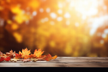 Naklejka na ściany i meble Wooden table with autumn leaves on bokeh background. Space for text or product display.
