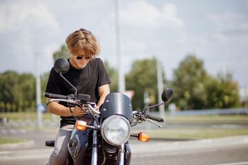 Fototapeta na wymiar male motorcyclist in sunglasses sits on a motorcycle on a sunny day. The concept of freedom on a motorcycle.