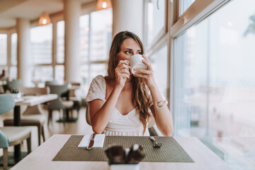 Chica joven tomando cafe en cafeteria de hotel - Powered by Adobe