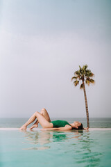 Chica joven delgada posando en piscina de hotel de vacaciones en traje de ba&ntilde;o