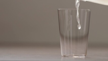 Slow motion pour lemon juice in tonic water into tumbler glass closeup