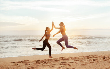 Glad young caucasian women enjoy morning workout, have fun, give high five, jump, freeze