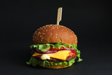 Delicious burger with beef patty and lettuce on black background
