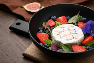 Delicious salad with brie cheese, blueberries and strawberries on wooden table, closeup